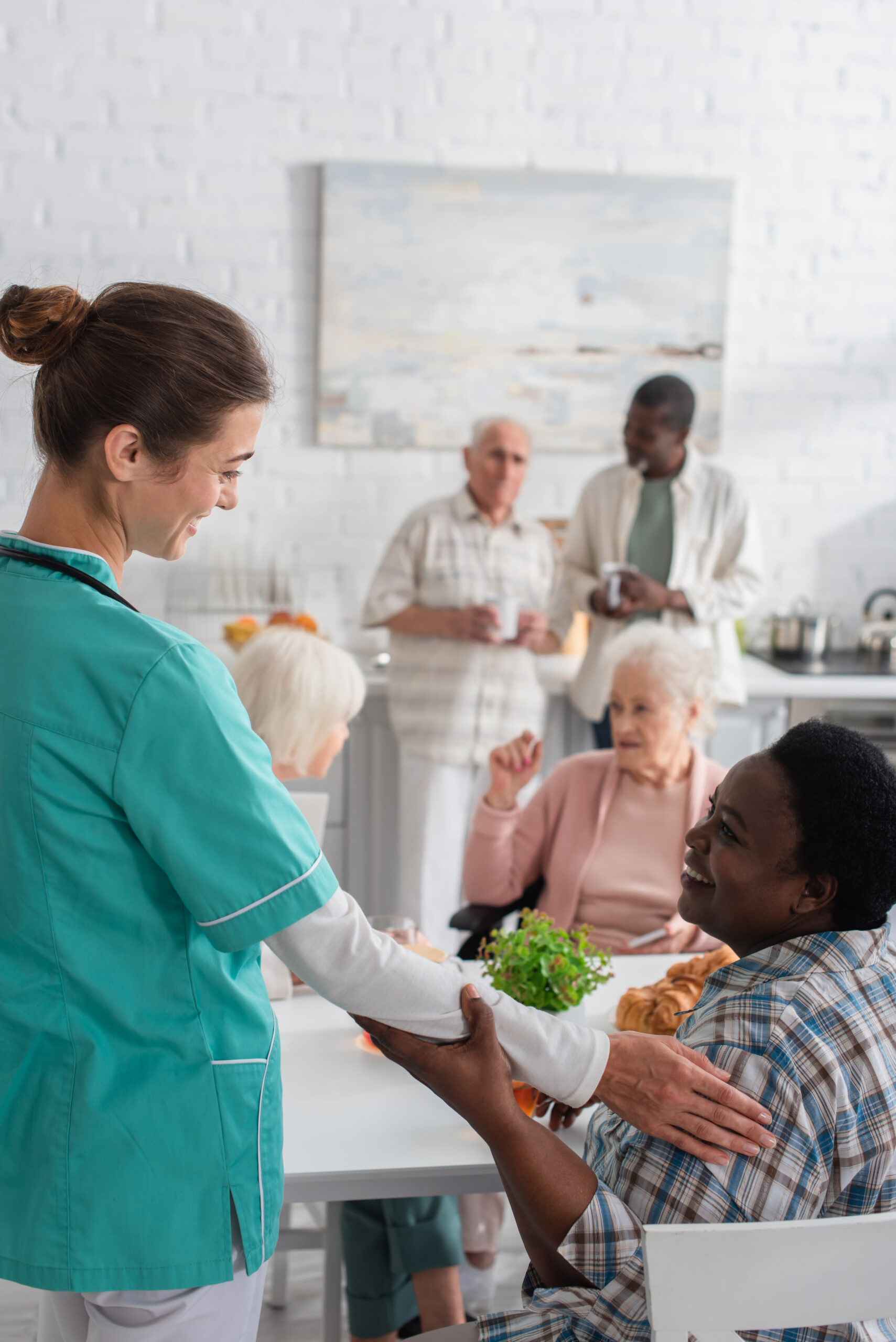 Smiling nurse touching elderly african american woman in nursing home